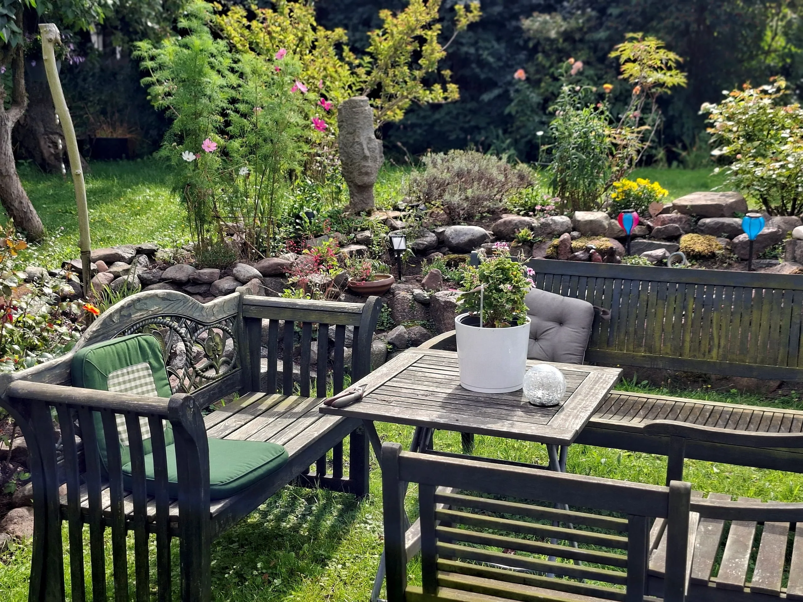 Ruhige Sitzecke im Garten mit Bank, Tisch und kleinem Steingarten